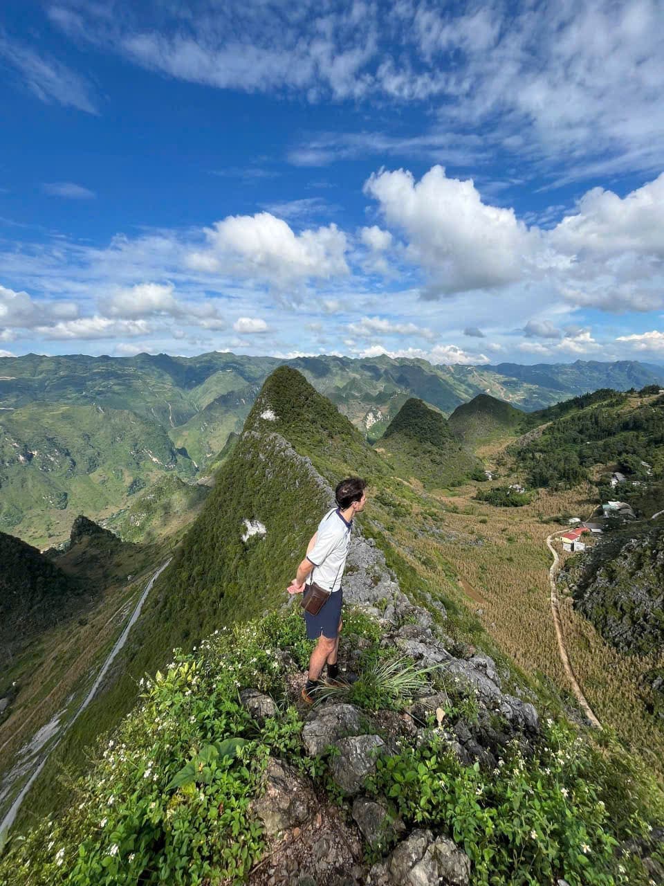 Traveler standing at a mountain viewpoint in Ha Giang with Vietnamese flag monument